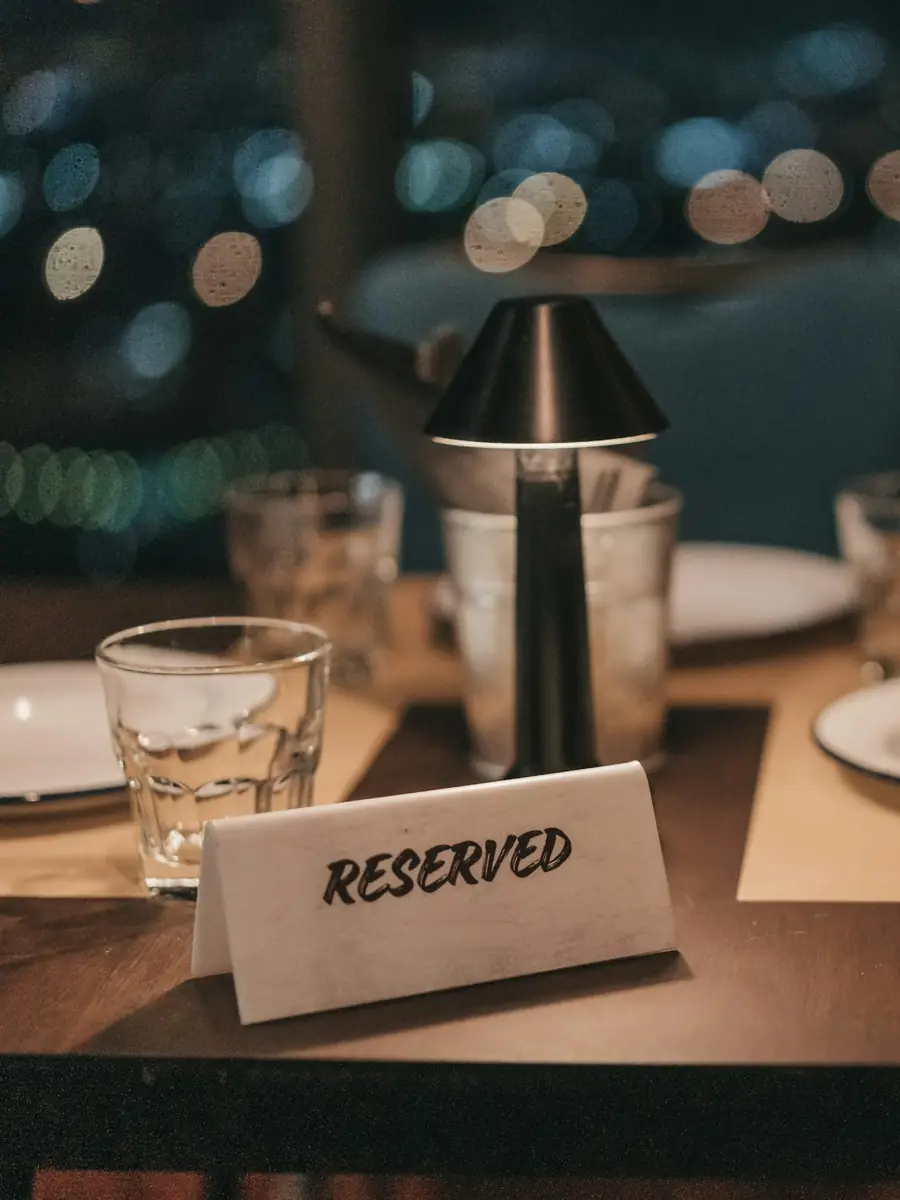 Un tavolo apparecchiato di sera con il cartoncino «reserved»