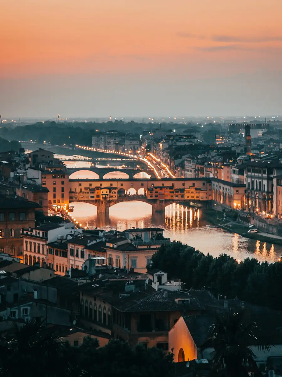 Il Ponte Vecchio e l'Arno a Firenze al tramonto, con le luci della città accese