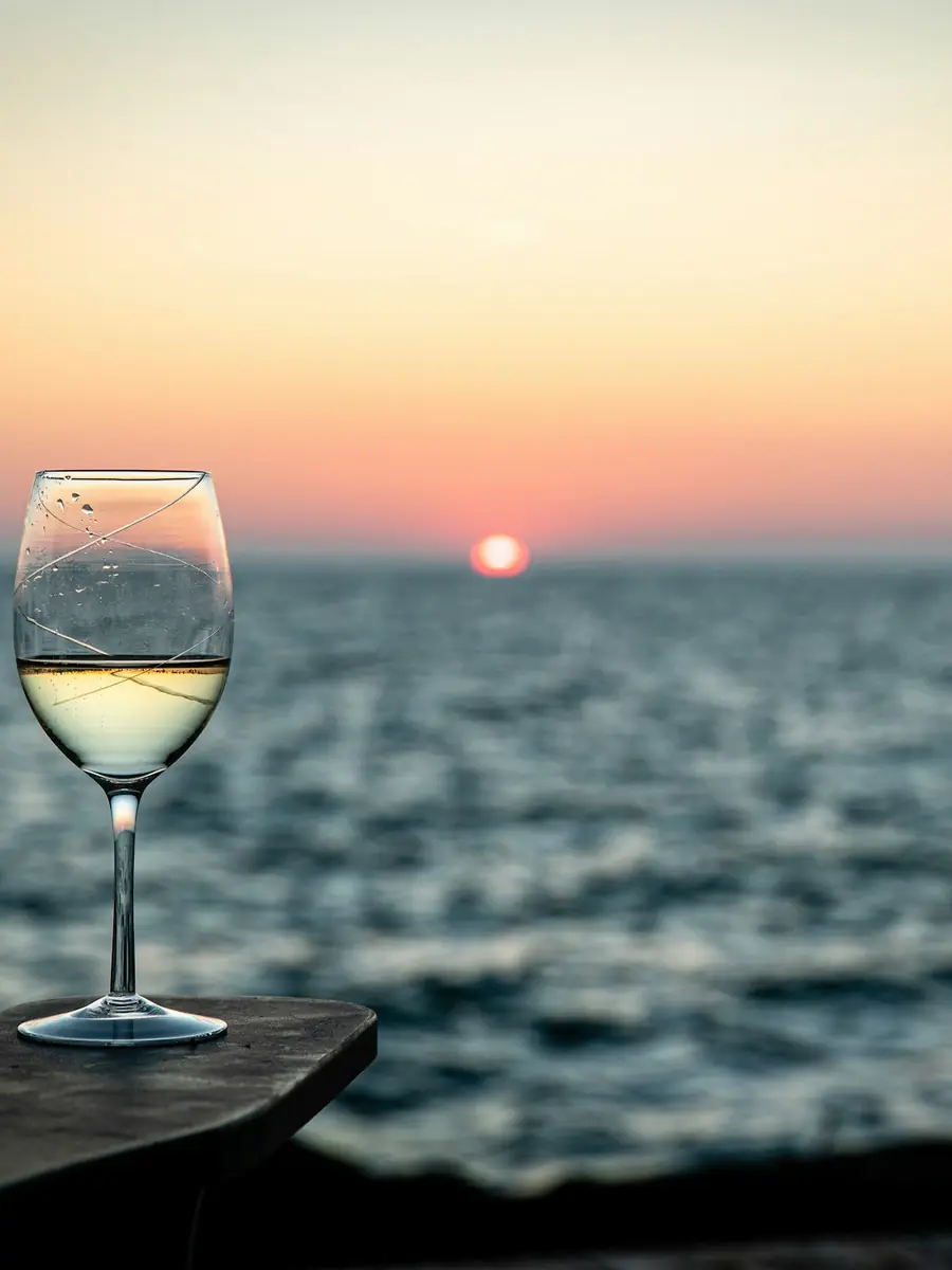 Un calice di vino bianco davanti al mare al tramonto